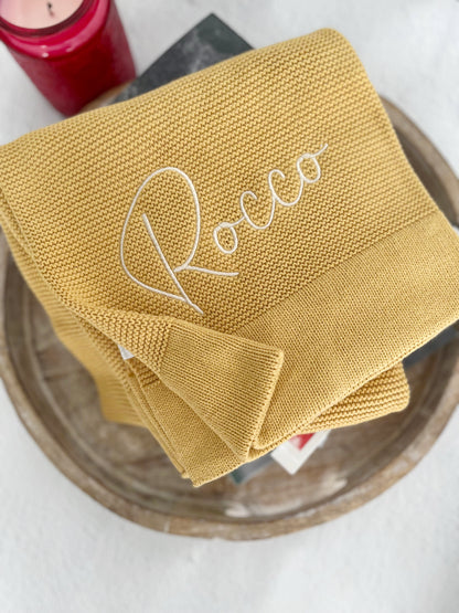 Mustard coloured cotton blanket embroidered with the name Rocco