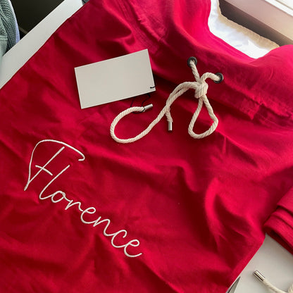Red garment with 'Florence' embroidery on a white surface