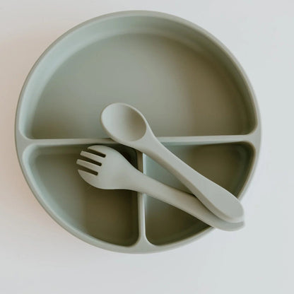 Children's green divided plate with fork and spoon on a white background