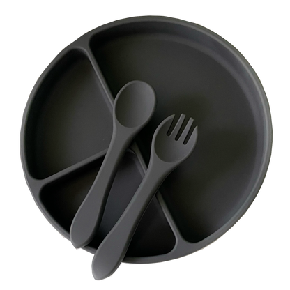 Black divided plate with spoon and fork on a white background